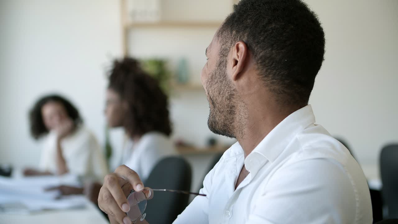 vista lateral de un hombre afroamericano riendo en la oficina.