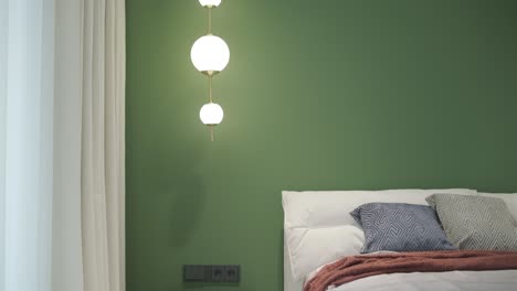 a serene bedroom scene with a plush bed adorned with a rust-colored throw, accented by a dark green feature wall and a view into a bright en-suite bathroom, evoking a sense of modern comfort