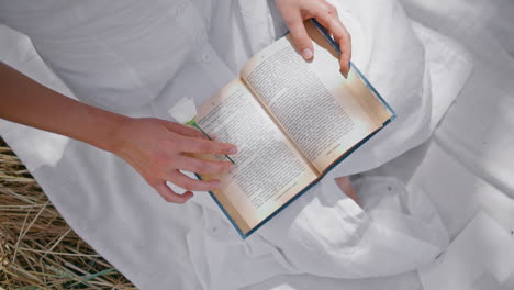 woman running fingers book pages at hay nature closeup. unknown lady reading