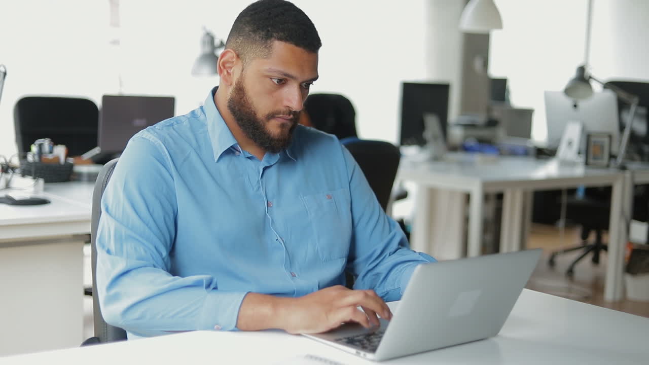 Concentrated businessman working with laptop in office.