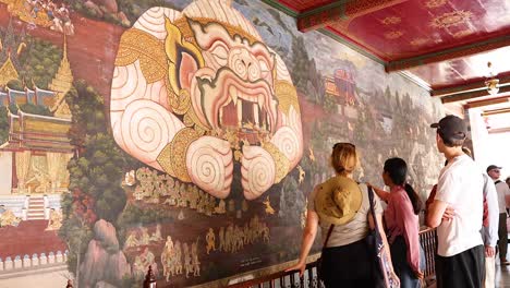 visitors observe intricate mural in bangkok temple