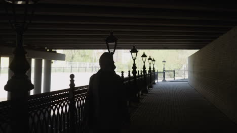 silhouette of arabic woman walking along shady embankment