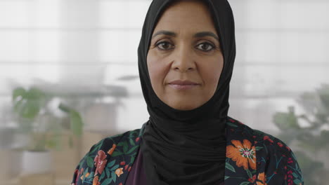 close up portrait of senior muslim business woman smiling looking confident at camera wearing traditional headscarf mature experienced female in office background