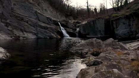 Langsamer-Drohnenflug-über-Wasser-In-Der-Nähe-Eines-Wasserfalls-Tagsüber