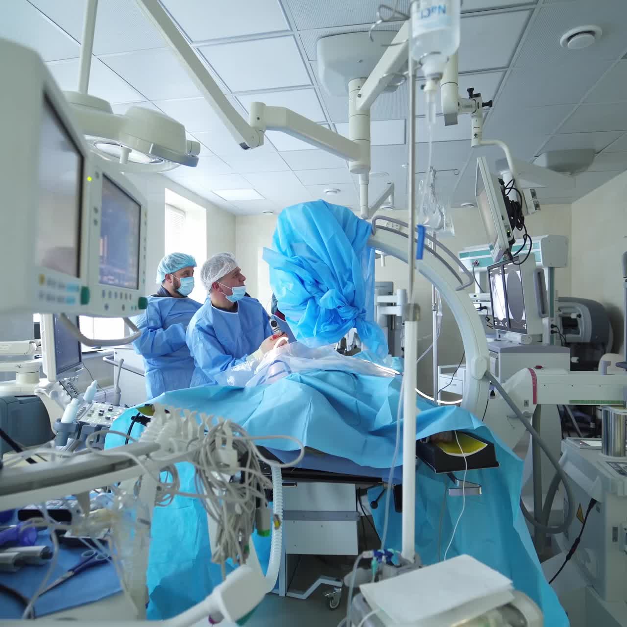 Group of surgeons at work. Surgical team in scrubs performing laparoscopic surgery on the patient in operating room