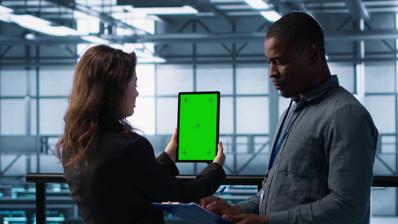 Teknikere i datacenter bruger tablet med grøn skærm og gennemgår hardware.