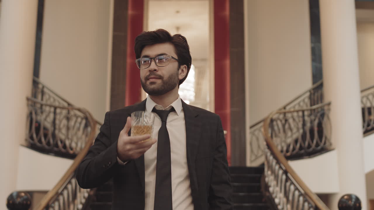 Uomo d'affari di successo con bicchiere di whisky che cammina