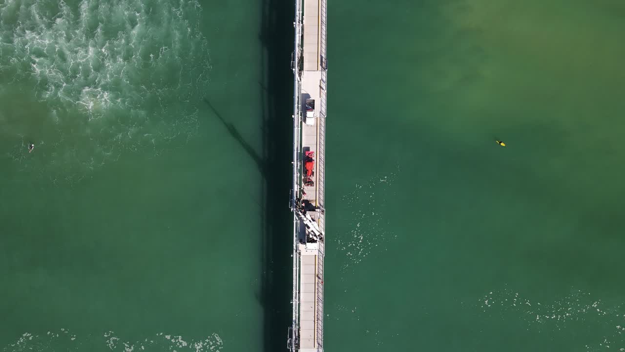 서퍼 들 이 바다 에 건설 된 큰 산업 플랫폼 근처 에서 파도 를 잡고 있다