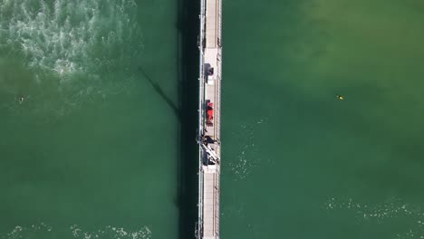 surfistas atrapando olas cerca de una gran plataforma industrial construida en el océano