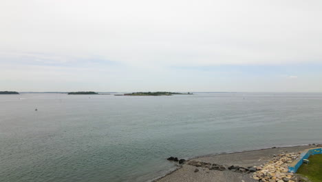 Aerial pull back showing Wind Turbine on Coast of Massachusetts, showing football field underneath