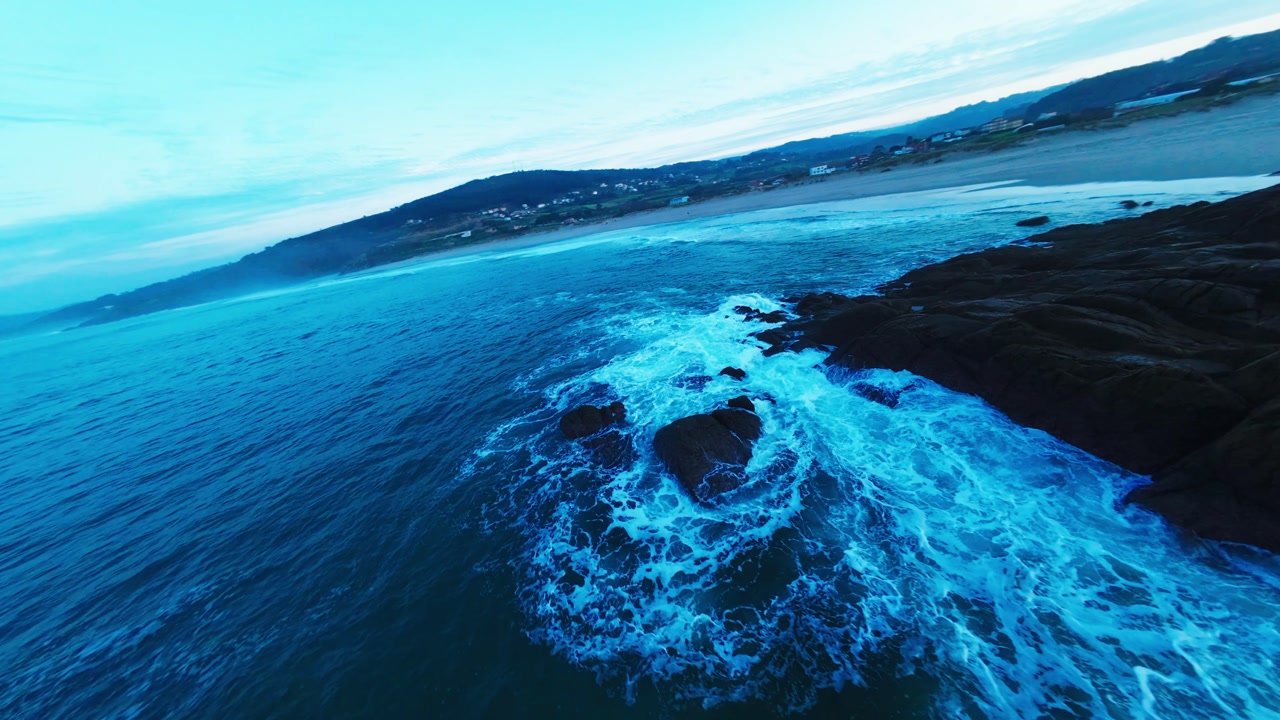 Aerial View Rocks In The Sea Next To A Beach With Foamy Waves At Sunset