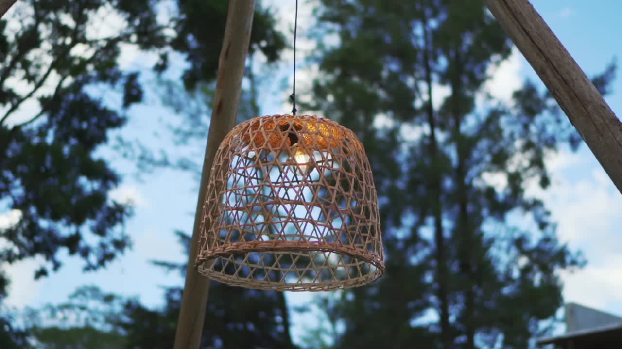 A lit wicker lamp hanging from the decoration of a night wedding outside