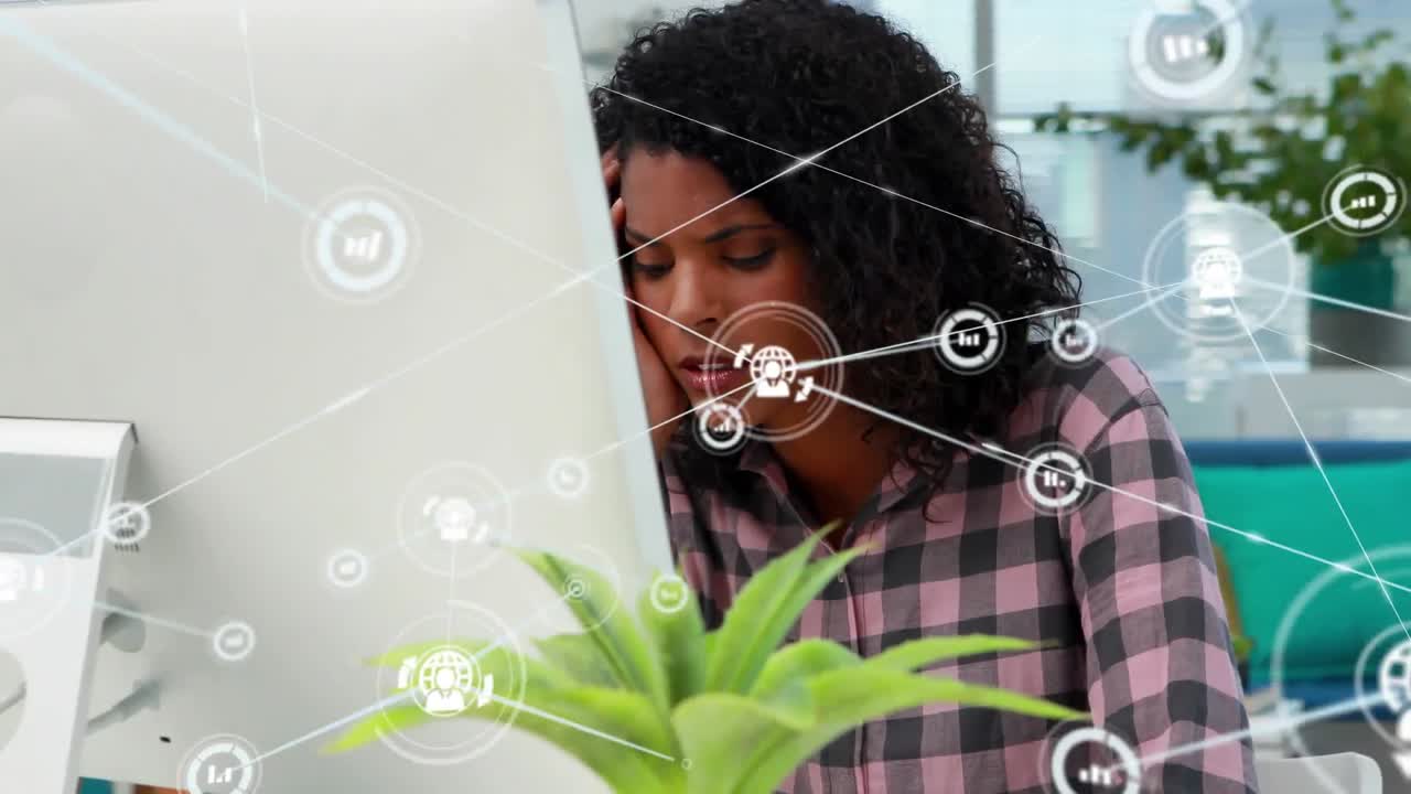 Animation of network of connections with icons over biracial businesswoman using computer in office