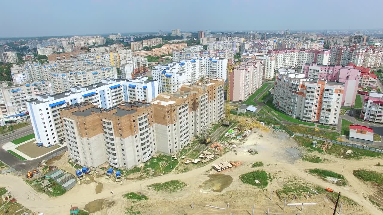 Flying over the construction site with a bird's eye in a city. New modern houses are building in a new residential complex. Aerial view