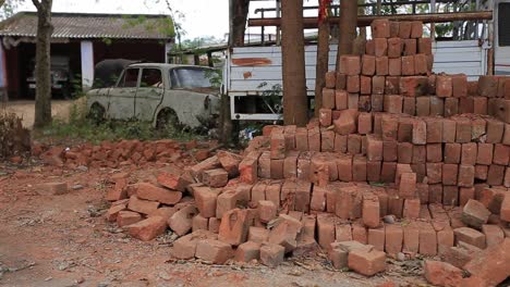 toma de las piedras de barro utilizadas para construir casas o edificios mantenidos frente a un camión y un automóvil debajo del árbol en un día brillante en sri lanka