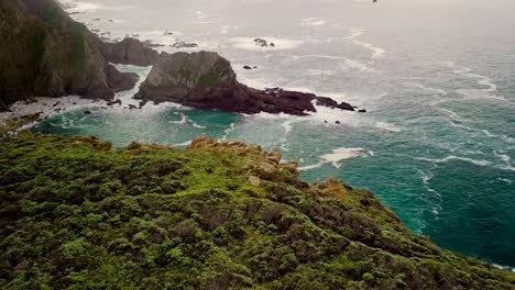 volando sobre el borde de un enorme acantilado mirando hacia abajo para revelar olas rompiendo en rocas en big sur california