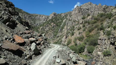 low aerial tracks narrow gravel road in bottom of rugged rock gorge