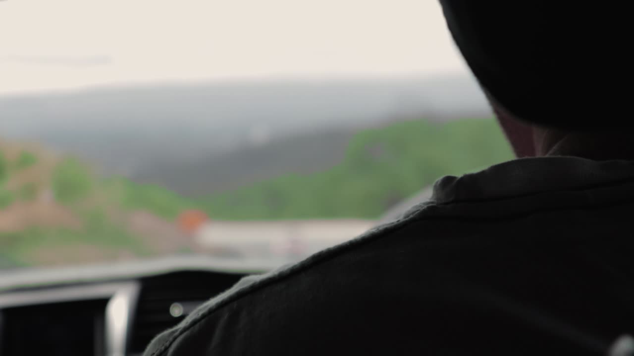 카메라가 그에게 초점을 맞추면서 한 남자가 슬로우 모션으로 차를 운전하고 있습니다.