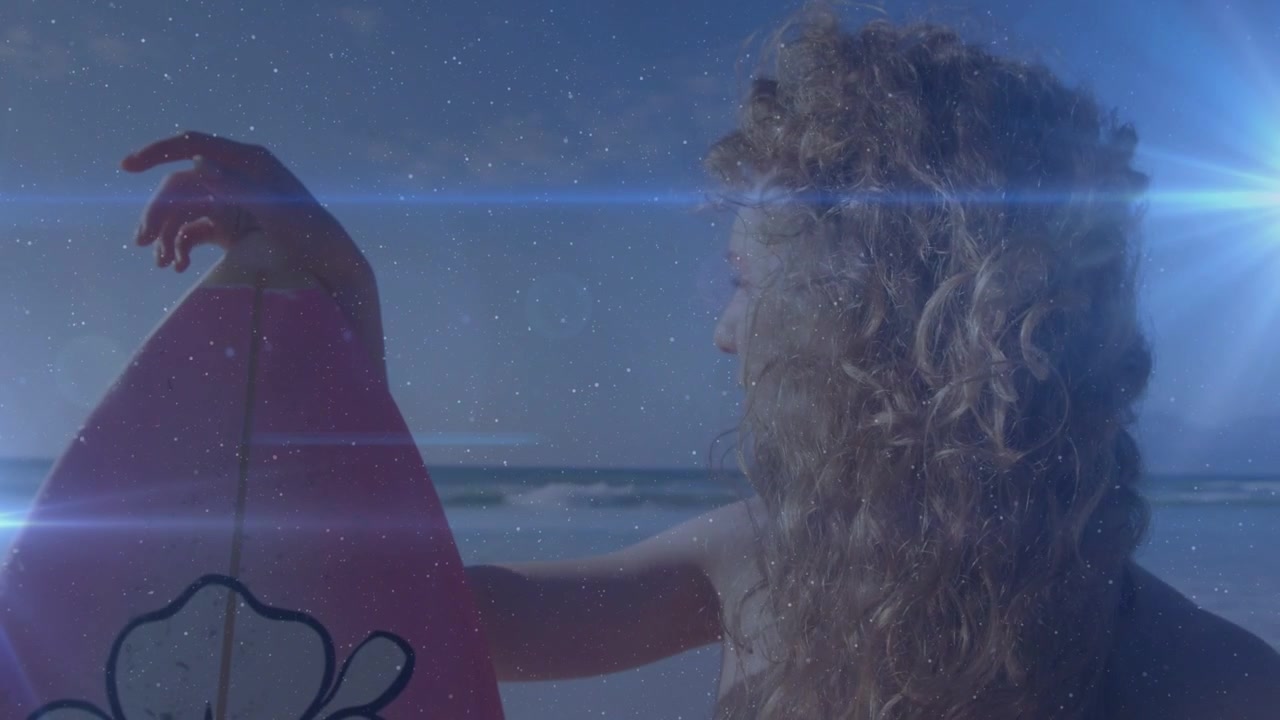 Donna che tiene una tavola da surf, individua le onde, si prepara a surfare, girandosi mentre i bagliori a stella si allungano per il viaggio.