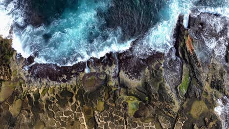 Top-Down-View-Over-A-Rocky-Shore-Line-with-salt-pans-and-Waves-Splashing