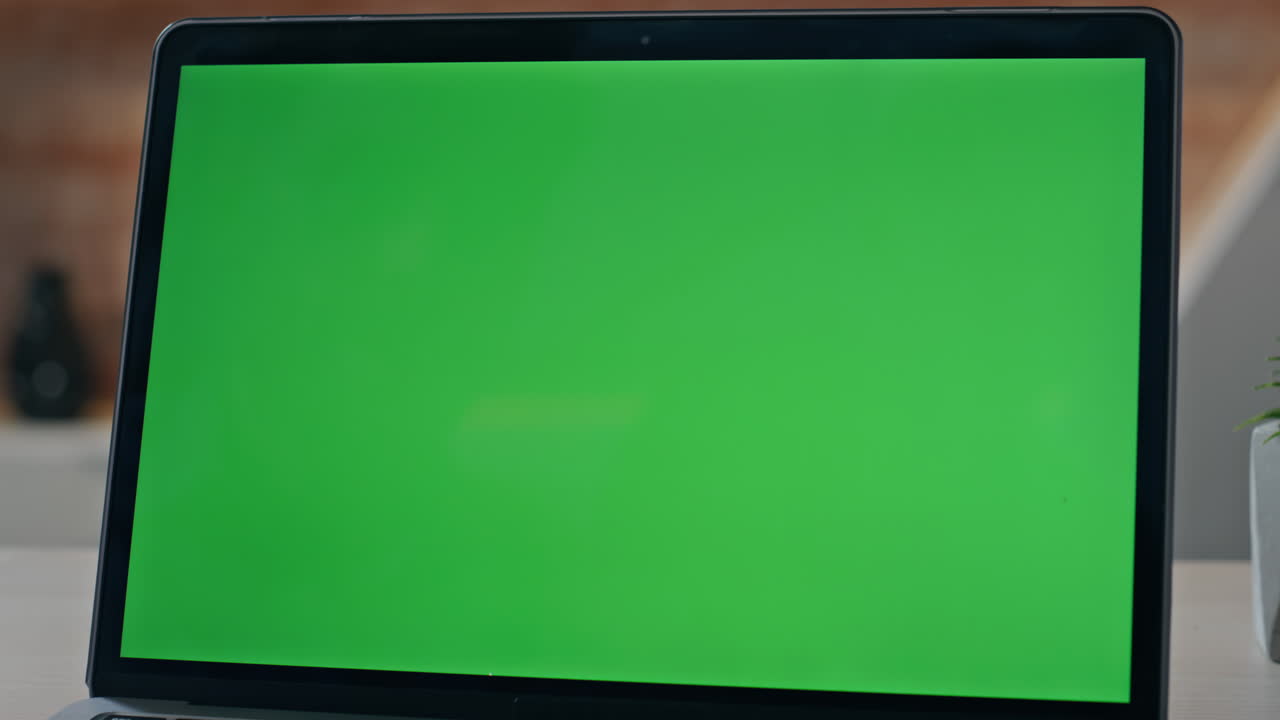 Monitor layar hijau kosong dari laptop modern berdiri di meja kantor, tampilan dekat.