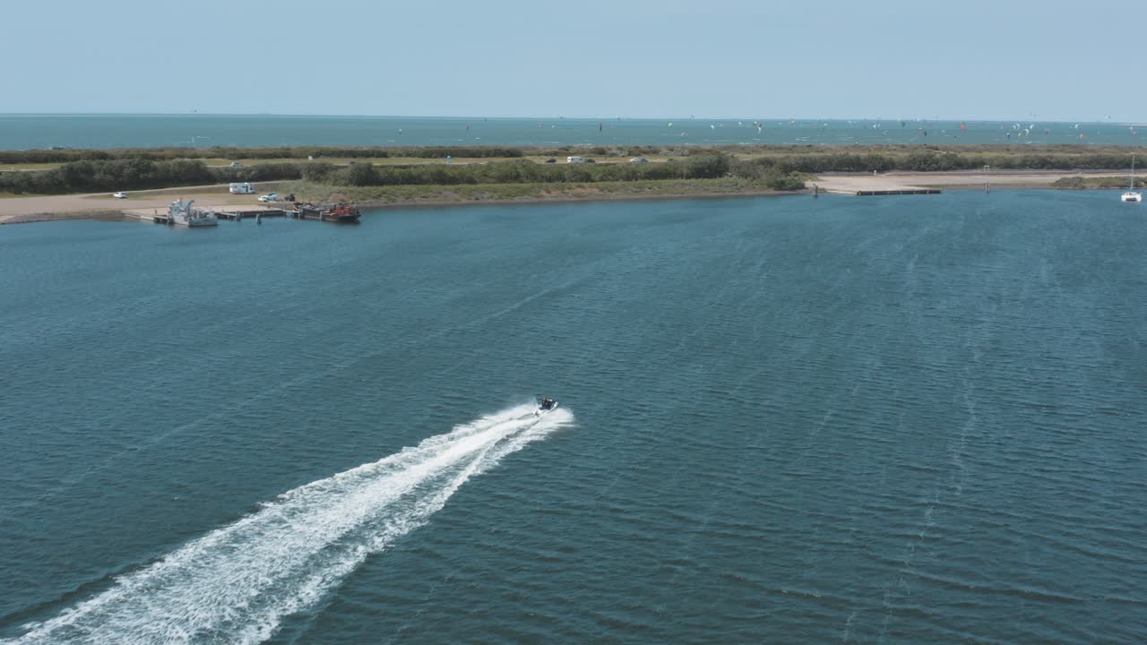 drone - toma aérea de un jetski en un mar azul, ondulado y ventoso en un día soleado con nubes blancas en una isla, 25p