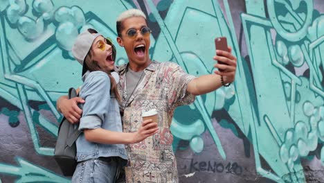 pareja divertida hipster con ropa elegante haciendo un selfie con un smartphone en la calle