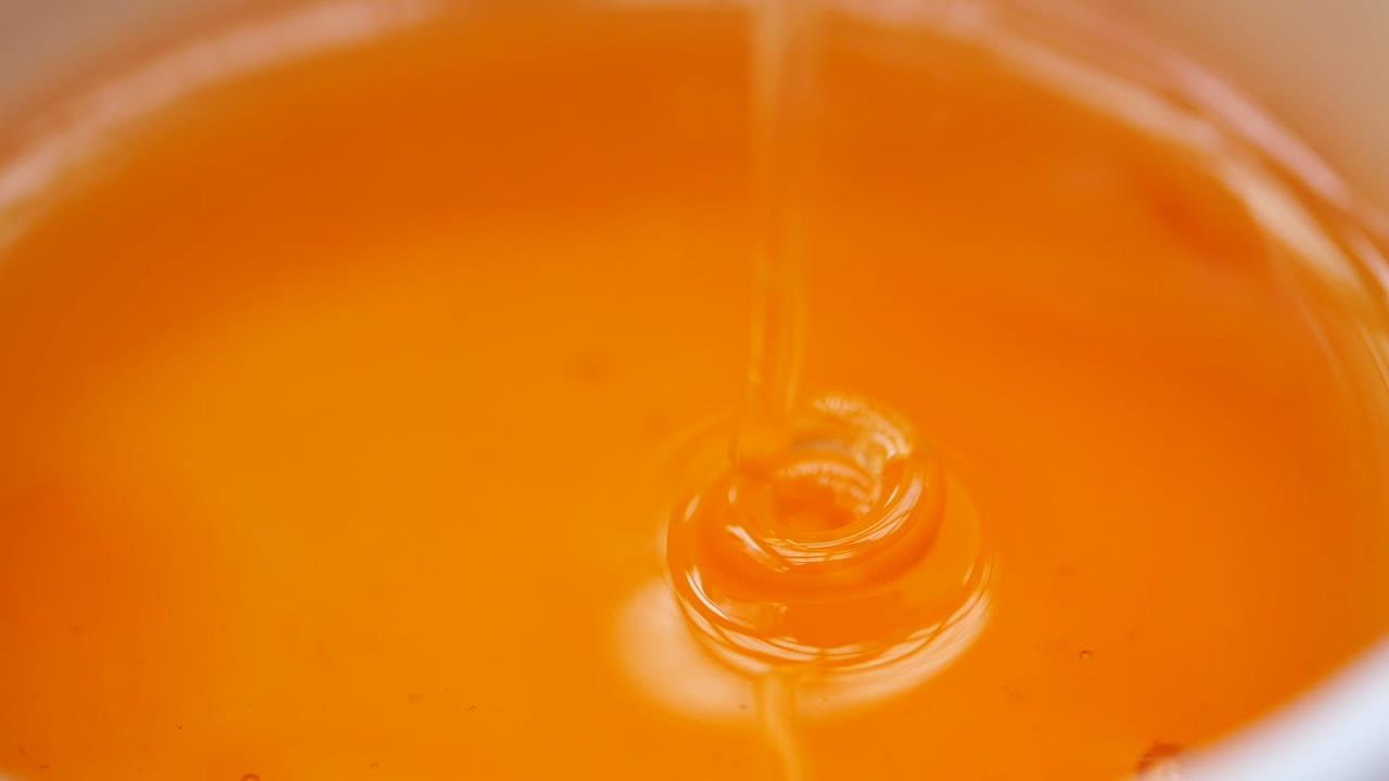 Golden honey dripping into a bowl