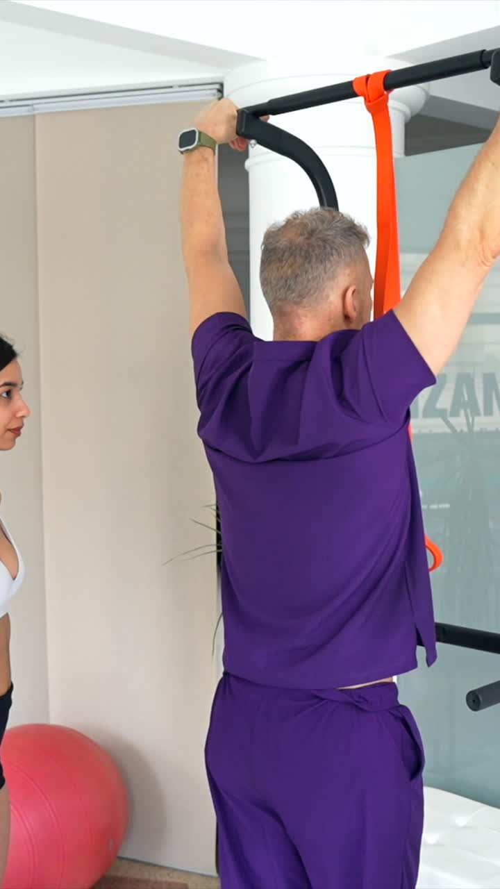 Homem Realiza Barras com Elástico de Resistência Enquanto Mulher Observa