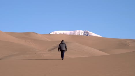 Man-walking-on-sand-dunes-in-slow-motion