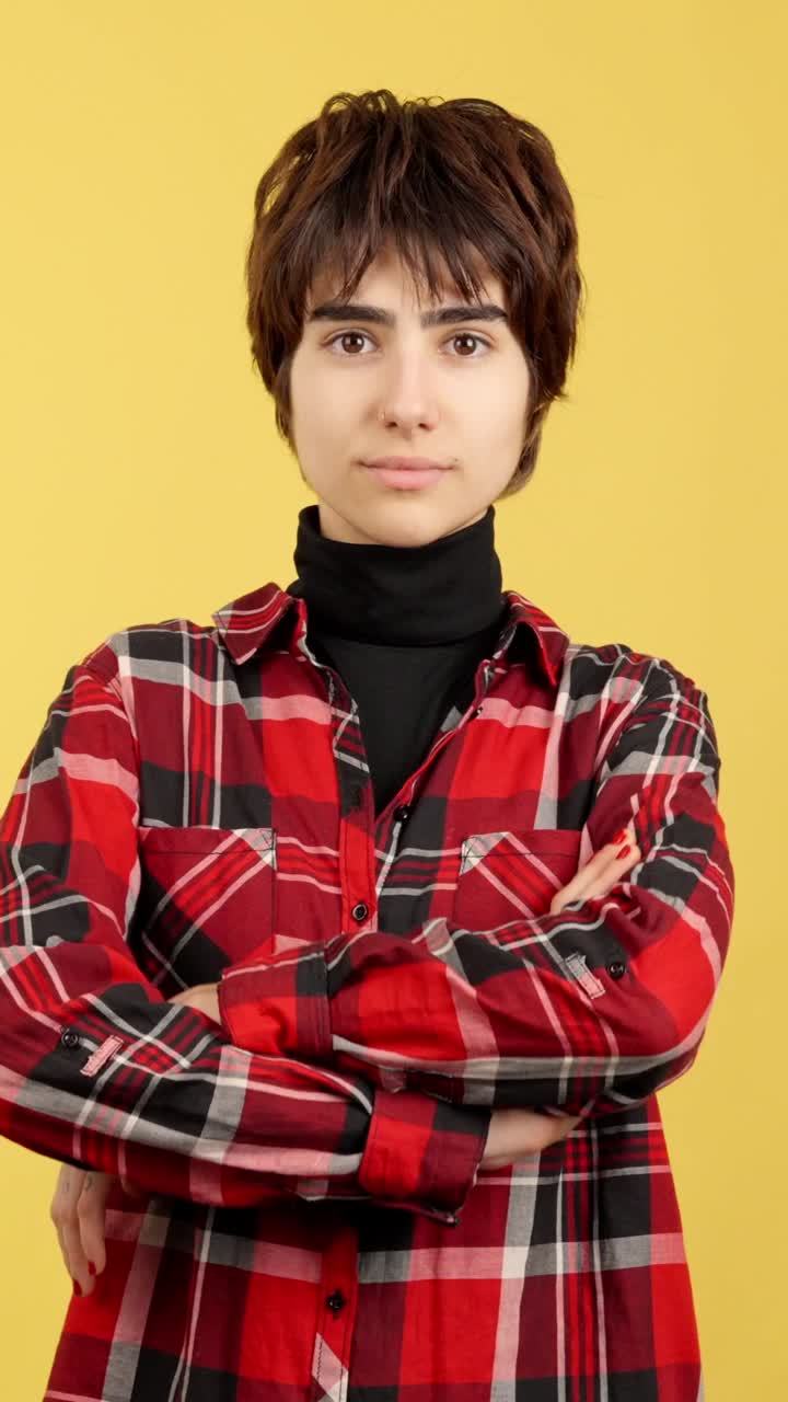 Portrait of a young person in a plaid shirt with arms crossed