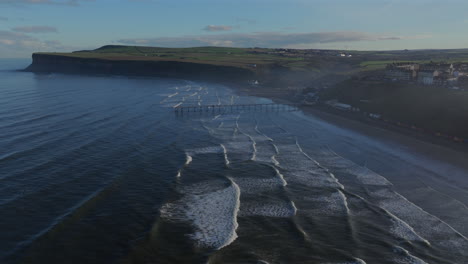 establishing drone shot of saltburn-by-the-sea and cliffs at high tide