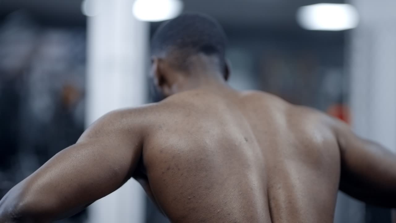 Muscular African American man doing cable chest pulls shirtless