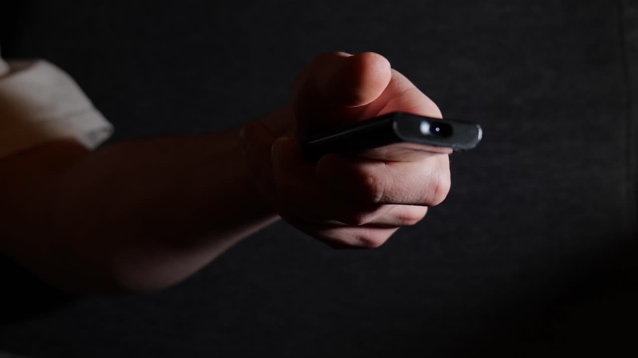 Person Browsing TV Channels With Remote Control Close-Up View