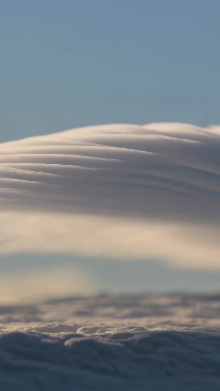 Video verticale: Grande formazione nuvolosa stratificata alla deriva che ondeggia all'alba sull'orizzonte marino, cielo sereno