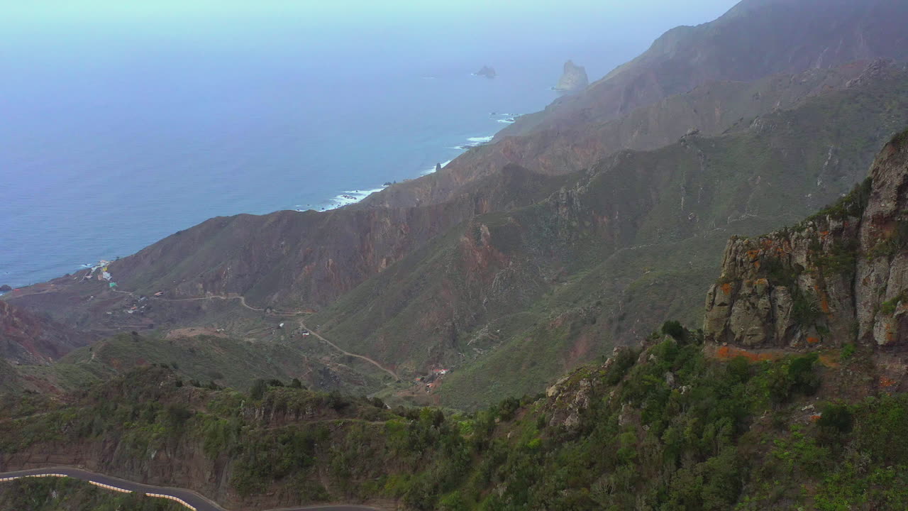 caminos asfaltados que serpentean a través de los altos acantilados y picos de las montañas en la isla canaria con pueblos en los valles y el océano atlántico debajo