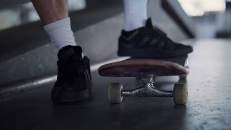 Unknown-man-legs-on-skateboard-outdoors.-Skater-having-break-at-skatepark.