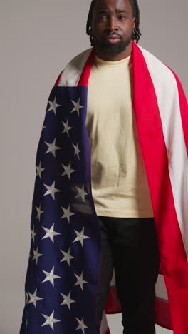 vertical video portrait shot of man wrapped in american flag celebrating 4th july independence day