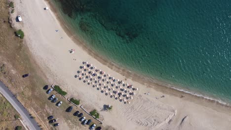 Greek-summer-|-Bird's-eye-view-descending-spinning-shot-of-golden-shores-in-the-Aegean-sea,-Greece-|-4K