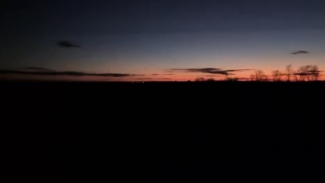 Driving-in-rural-field-area-during-sunset-sundown-in-dark-evening-night