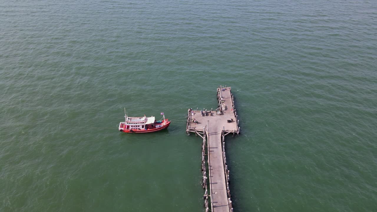 새가 날아 다니는 동안 정박 한 어선과 일부 오토바이를 드러내는 파타야 낚시 부두 끝의 공중 고정 영상, 파타야, 태국