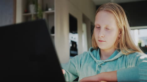 un niño usa una computadora portátil en la cocina de su casa. concepto de aprendizaje a distancia