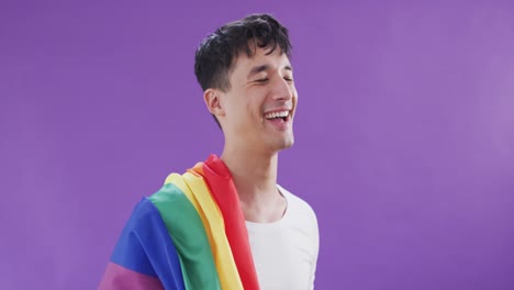 Happy-biracial-man-holding-lgbt-flag-on-shoulder-and-smiling