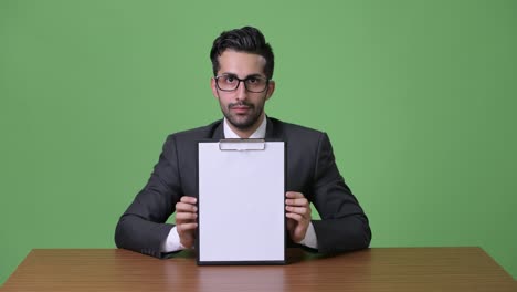 young handsome bearded persian businessman against green background