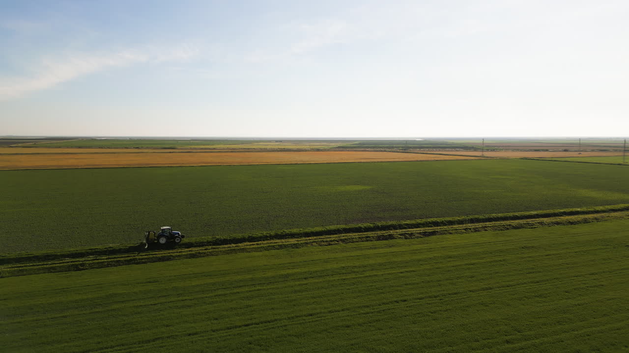 Green farm fields and lonely tractor, aerial view