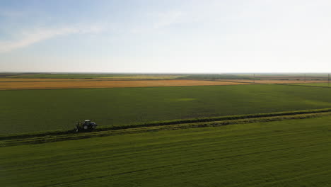 green farm fields and lonely tractor, aerial view