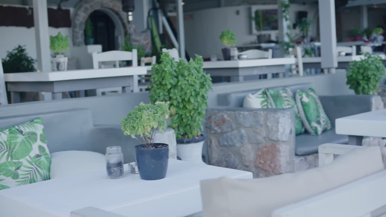 Modern furniture at a outdoor bar as waiter walks in background in Santorini, Greece