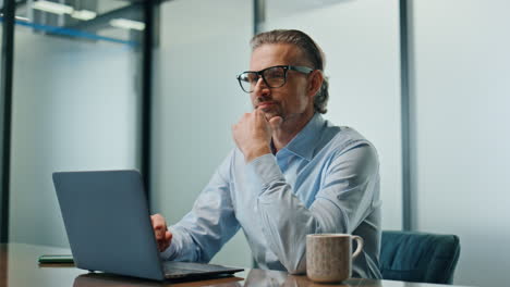 focused businessman typing laptop office closeup. satisfied man looking distance