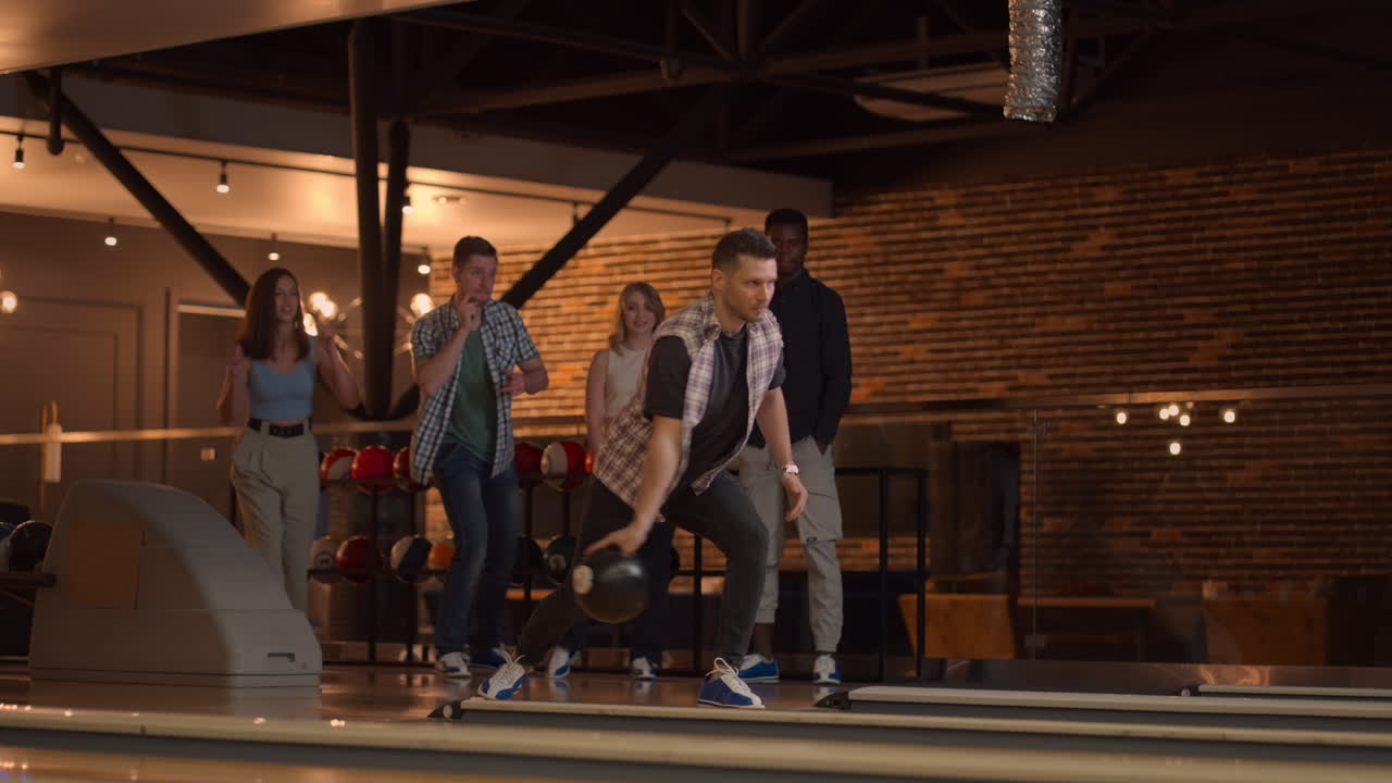 Piano generale: Un giocatore di bowling lancia una palla con il supporto degli amici ed esulta facendo strike