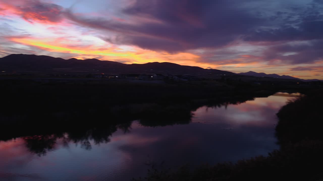 Panning shot of a stunning sunset with brilliant colors reflecting off a calm river